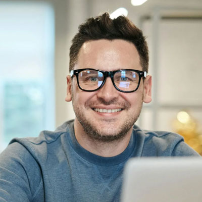 Portrait of Dee, smiling, wearing glasses